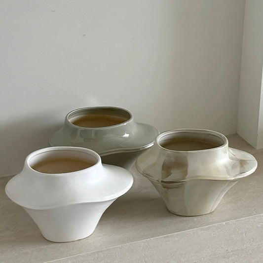 Three ceramic bowls of different shapes and sizes on a light surface with a neutral background.