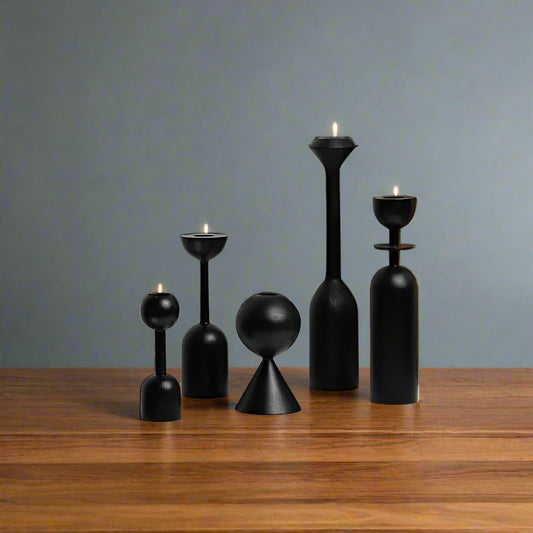 Set of black vases on a white surface with a wooden board in the background