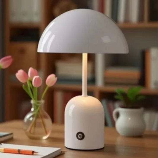 White table lamp on a wooden desk with pink tulips and a notebook in a cozy room.