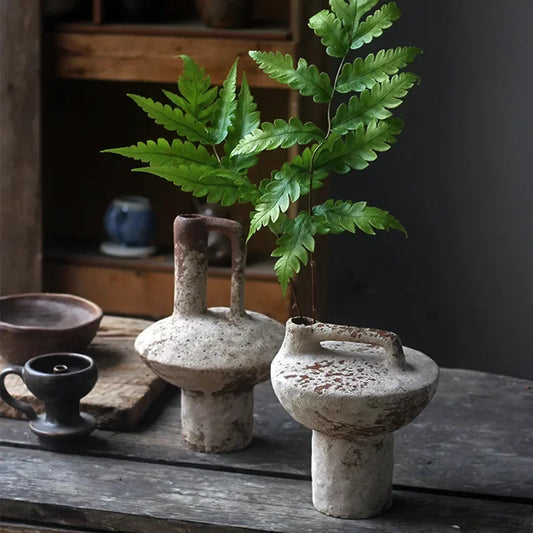 Two ceramic vases with a plant on a wooden surface