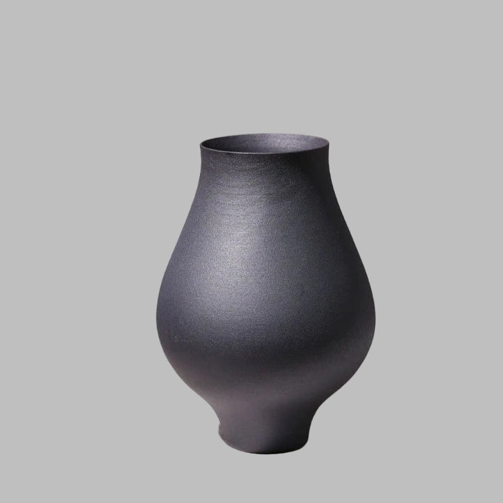 Black textured vase on a light surface with a gray background