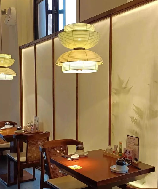 Restaurant interior with wooden tables, chairs, and hanging lights.