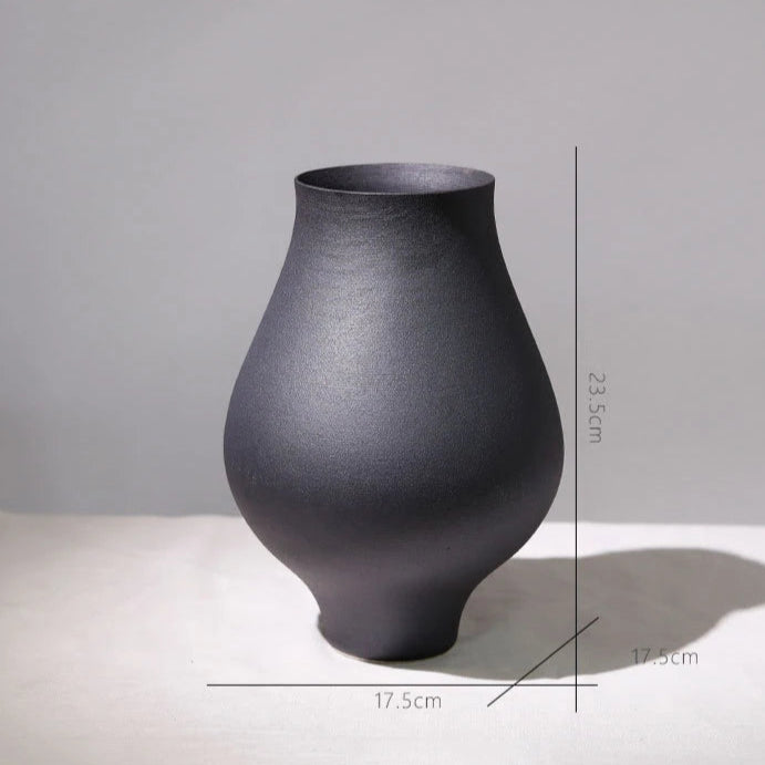 Black vase on a light surface with a gray background, featuring measurements.