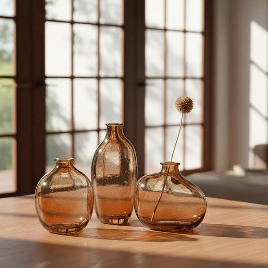 Three amber glass vases on a light surface with a white background