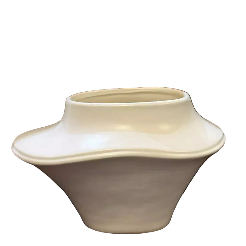 White ceramic vase on a reflective surface with a brown background