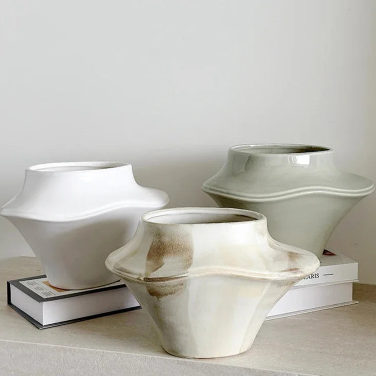 Three ceramic vases on a light surface with a neutral background