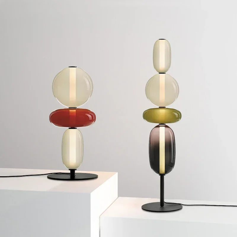 Two modern table lamps with colorful glass shades on a white surface.