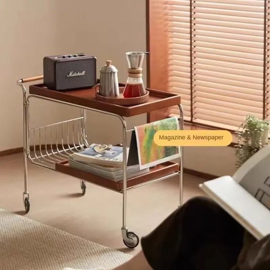Wooden serving cart with Marshall speaker, coffee maker, and magazines in a room with a window and rug.