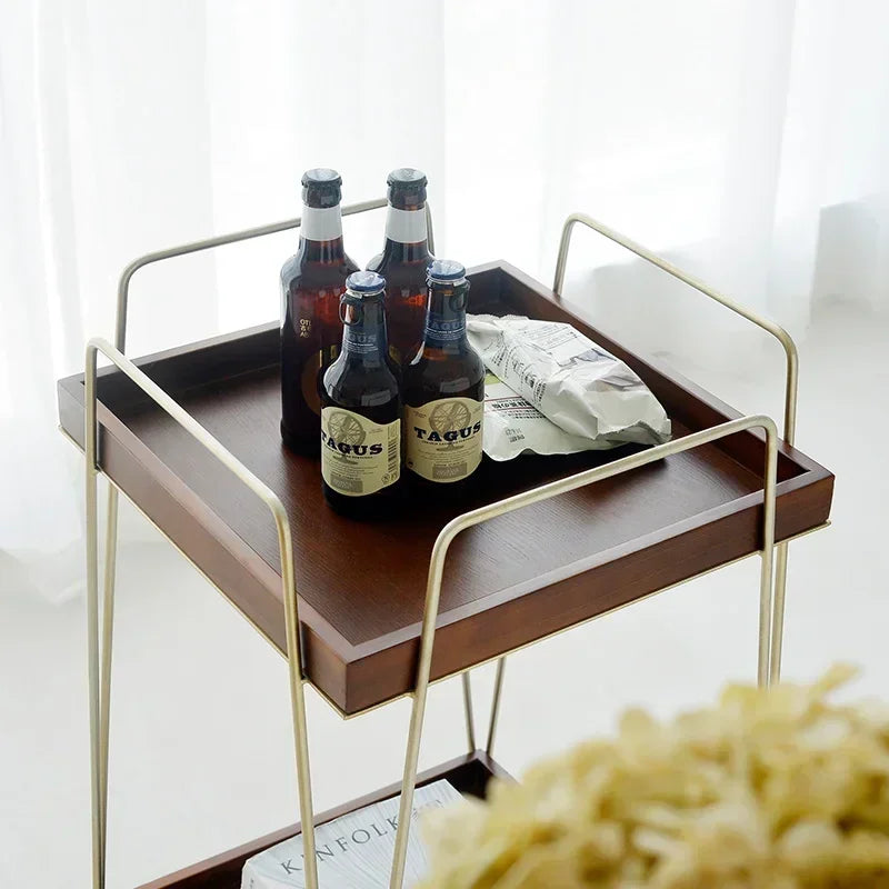 Mabel rolling wood cart with drinks and snacks on a brown tray and brass frame, perfect for entertaining.