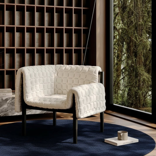 White quilted armchair in a modern interior setting with a bookshelf and window.