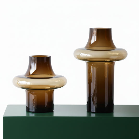Two brown glass vases on a white surface with a neutral background