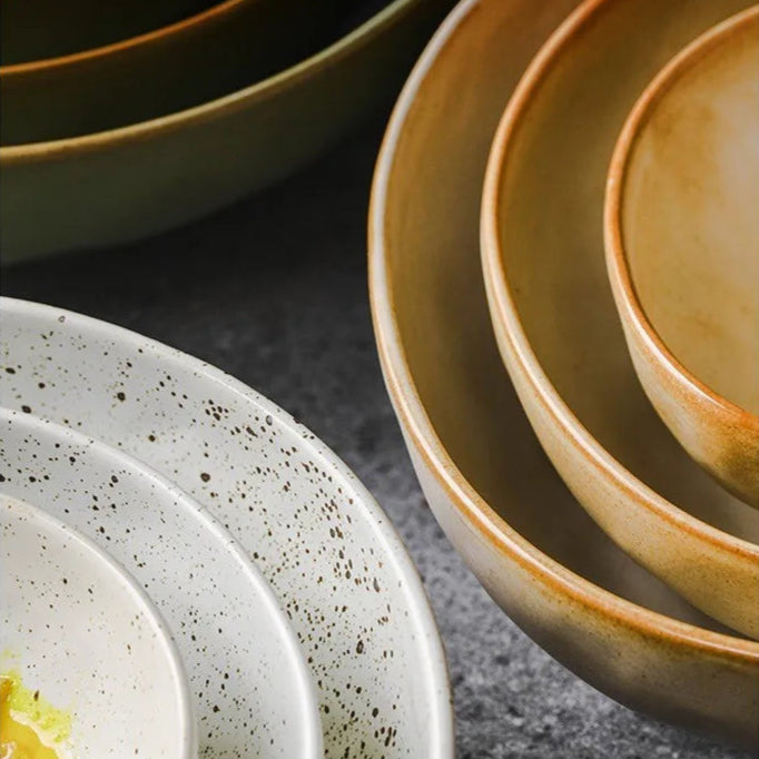 Set of ceramic bowls with rounded edges on a dark surface