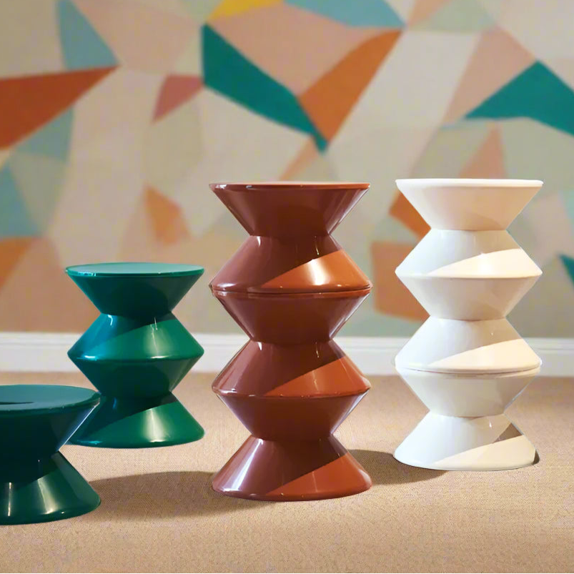 Colorful geometric stools arranged in a row against a neutral wall.