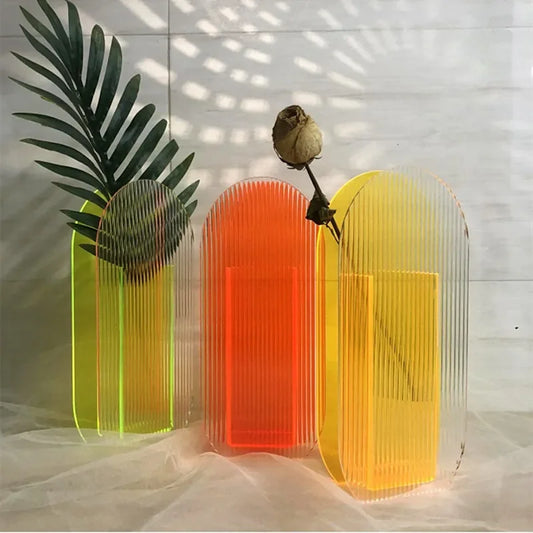 Three translucent vases in green, orange, and yellow on a light background