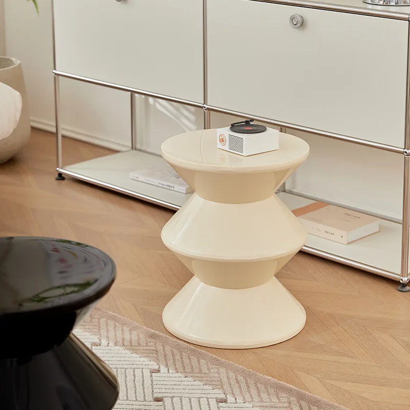 White side table in a room with a cabinet and books on a wooden floor.