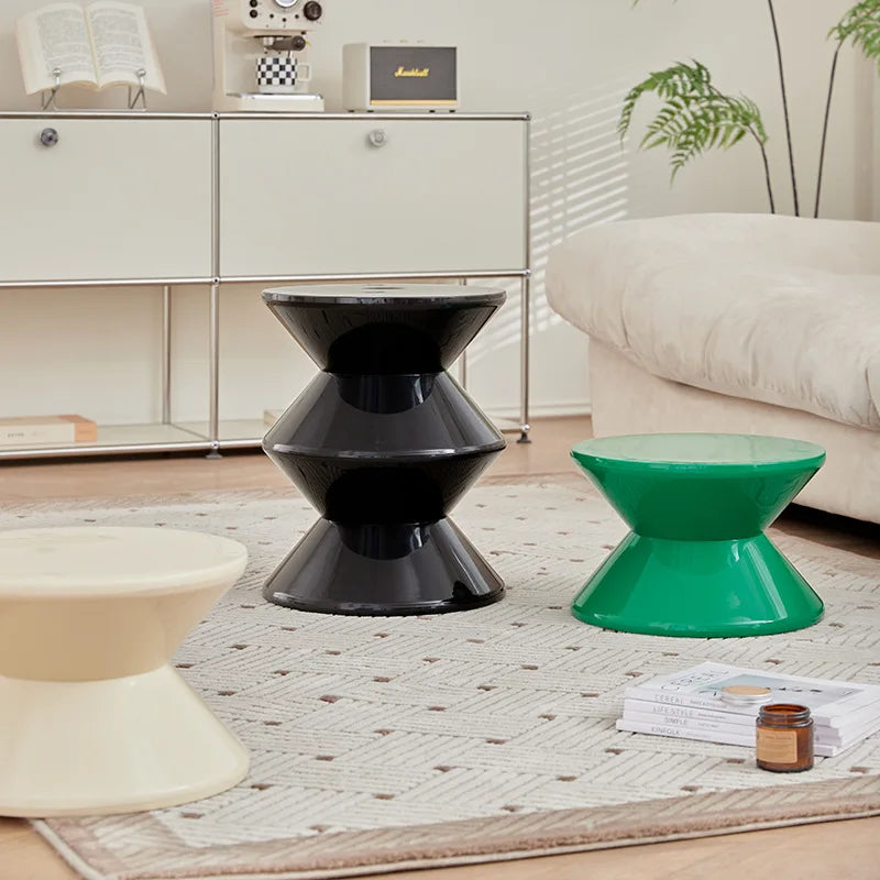 Three modern stools in black, green, and beige on a rug with a neutral background.