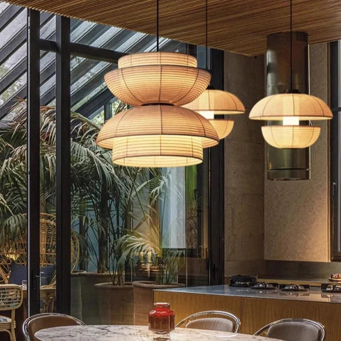 Modern interior with mismatched pendants, set around tables, and chairs in an open kitchen dining setting.